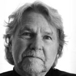 Black and white headshot of a man with white hair and a black shirt.